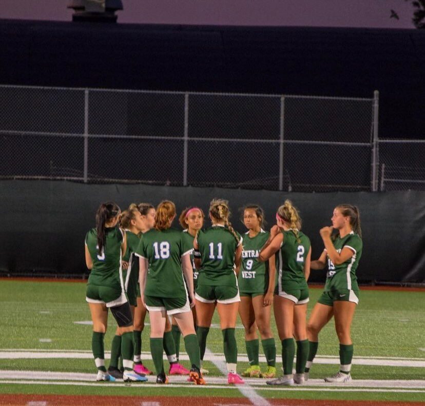 Central girls' soccer team in a tactical huddle at midfield